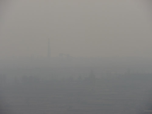 A smokestack disappears in the haze