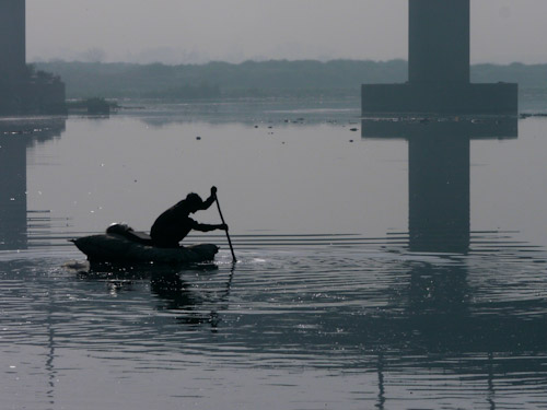 A man paddles across the Yamuna River