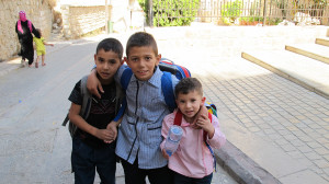 Three children wearing school backpacks in Tyre