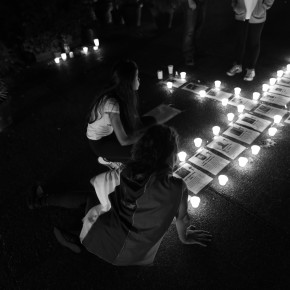 Protesters sitting alongside candles and photos of the dead