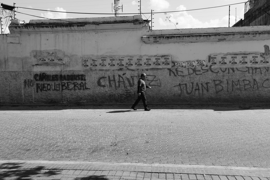 Man walking past graffiti-marked wall in Caracas