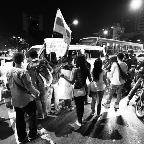 Protesters holding a flag and flagging passing cars