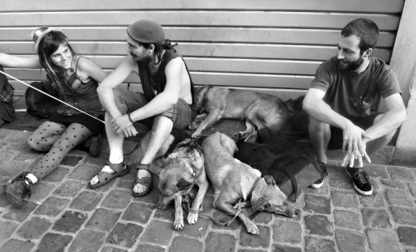 Street people entertain passersby with balloons while their dogs rest