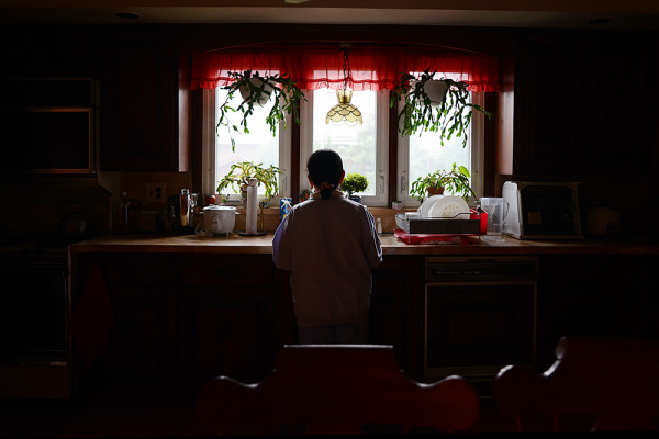 Myra, an undocumented Filipina immigrant, looks out the kitchen window of a friend's home on Staten Island