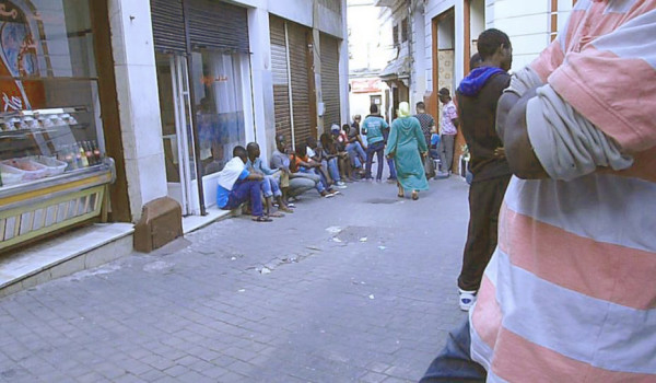 African immigrants squatting in the street in front of a Senegalese restaurant