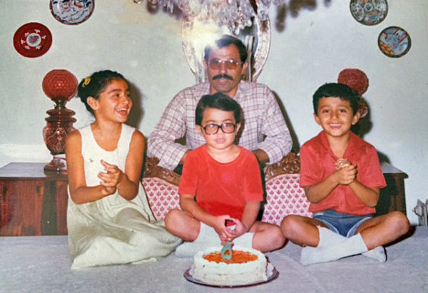 Bahar Anooshahr, her father, and her two brothers in front of a birthday cake