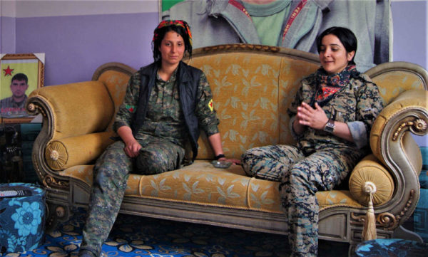 Two female YPJ soldiers sit on a couch