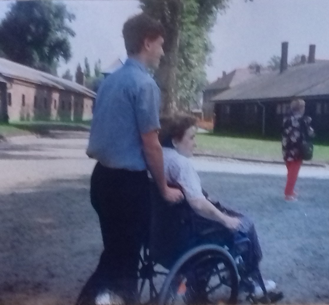 Jan Vihan pushing a woman in a wheelchair through Auschwitz