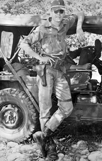 Bob Keeler standing in front of an Army jeep