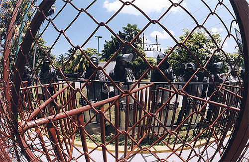 Fisheye view of the security fence with riot police behind it