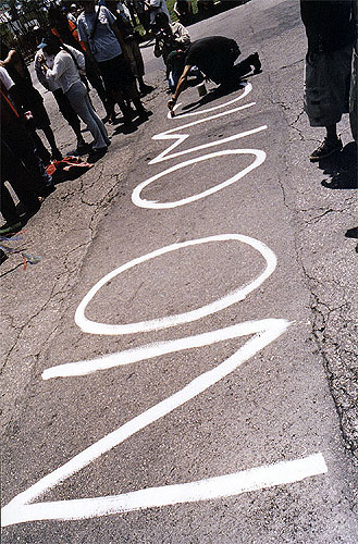 Protester painting "OMC" in white letters on the asphalt