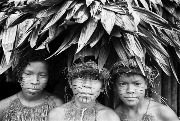 Three children with painted faces underneath a tree