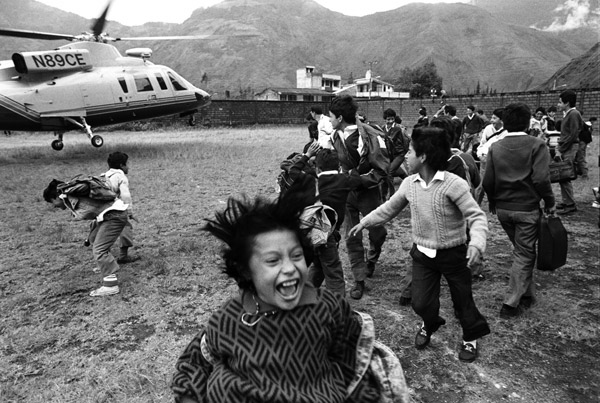 Children laughing and watching helicopter land