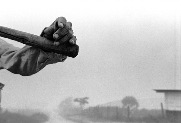 Man's hand carrying a pickaxe against the fog