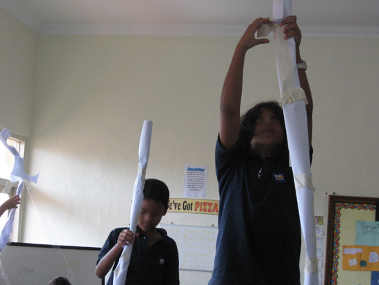 Two boys building a tower made of paper towels in a classroom