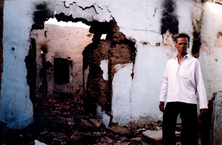 Former resident stands in front of his destroyed home