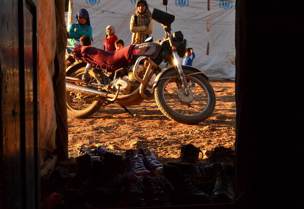 Women behind a motorcycle and in front of tents