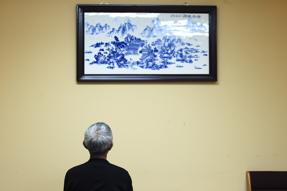 Chinese immigrant facing a traditional Chinese landscape painting