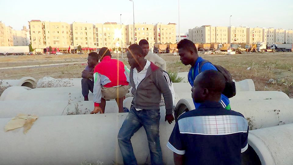 African men in Tangier sit among the concrete pipes they sleep in