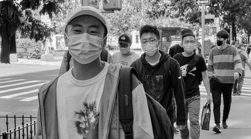 Masked young Asian American men walking down the sidewalk