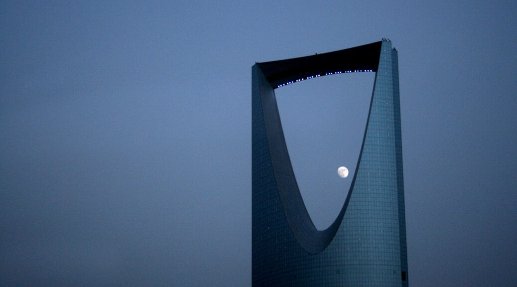 Close-up of top of the Kingdom Centre building, with a full moon visible under the skybridge