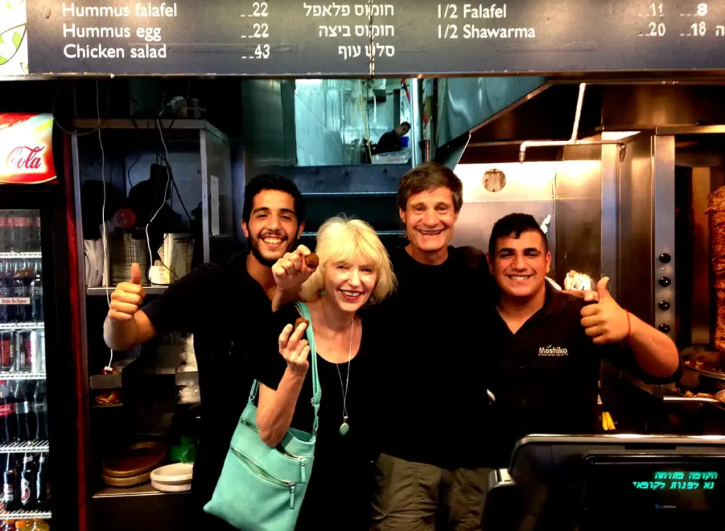 Two workers in black shirts flanking the author and his wife Mardena.